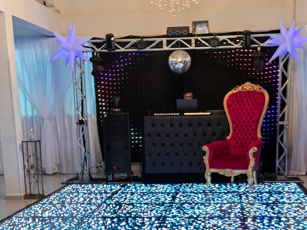 Cabine do DJ com globo espelhado, poltrona vermelha e pista de LED no salão Hibisco