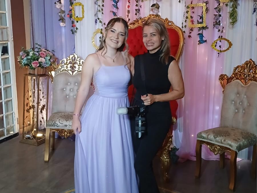 Fotógrafa com a câmera ao lado da debutante, diante do trono e do mosaico de hibisco